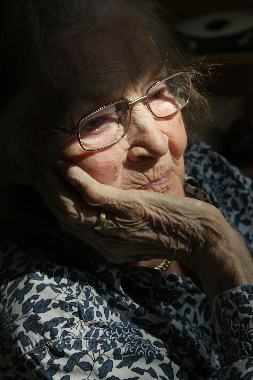 An image of an old woman sitting and looking into the distance.
