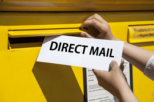 An image of someone putting a direct mail piece in a mailbox. 